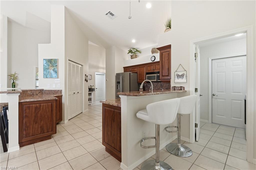 Kitchen featuring wood-finish cabinetry, stone countertops, and a breakfast bar with built-in seating