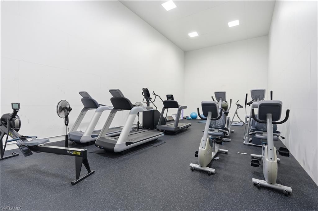 Dedicated fitness room featuring resilient rubber flooring, recessed ceiling lighting, and stark white wall finishes