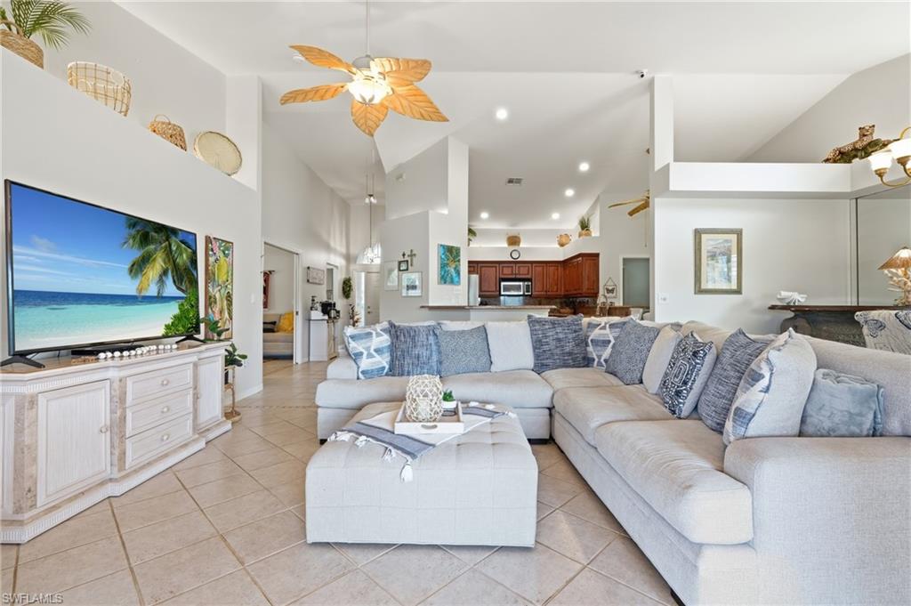 Spacious living area featuring vaulted ceilings, neutral tile flooring, and recessed lighting