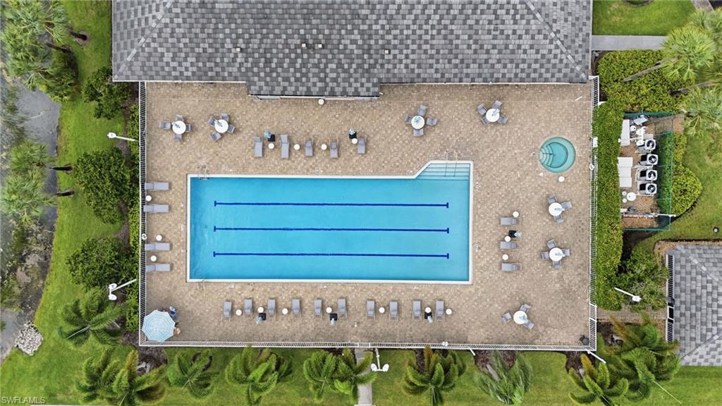 Outdoor recreational area featuring a large swimming pool with lane lines, a circular spa, and an extensive paver deck