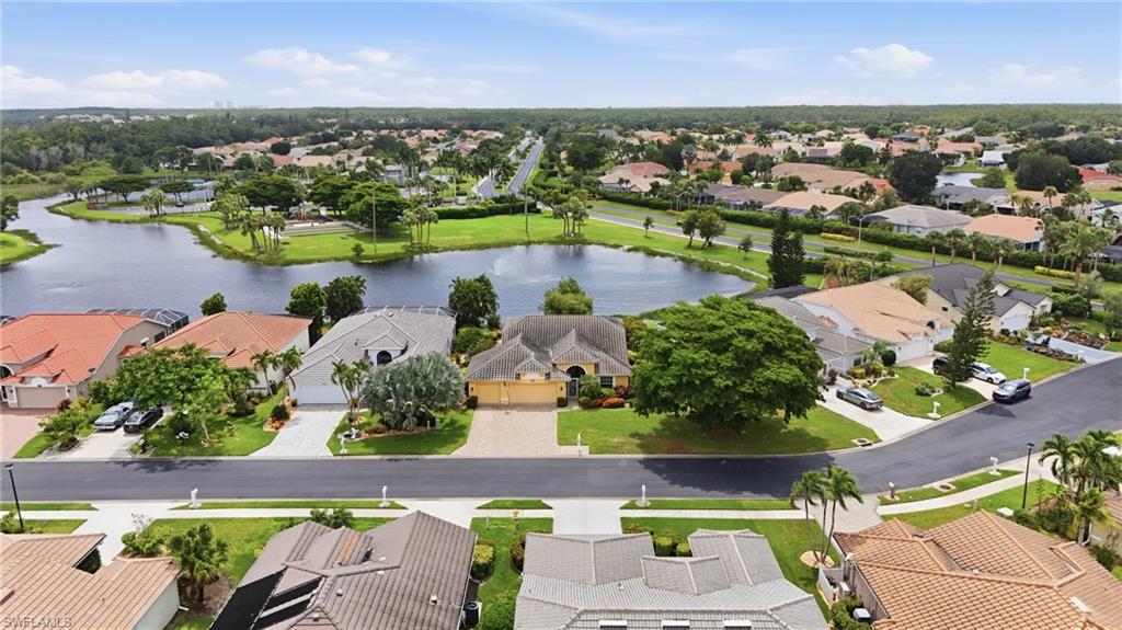 Residential property featuring a paved driveway, a manicured lawn, and mature trees