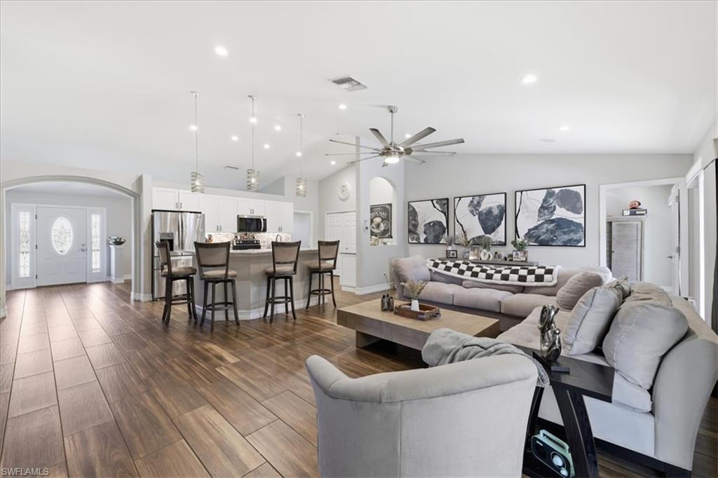 Open-concept living space featuring wood-finish flooring, vaulted ceilings, and recessed lighting