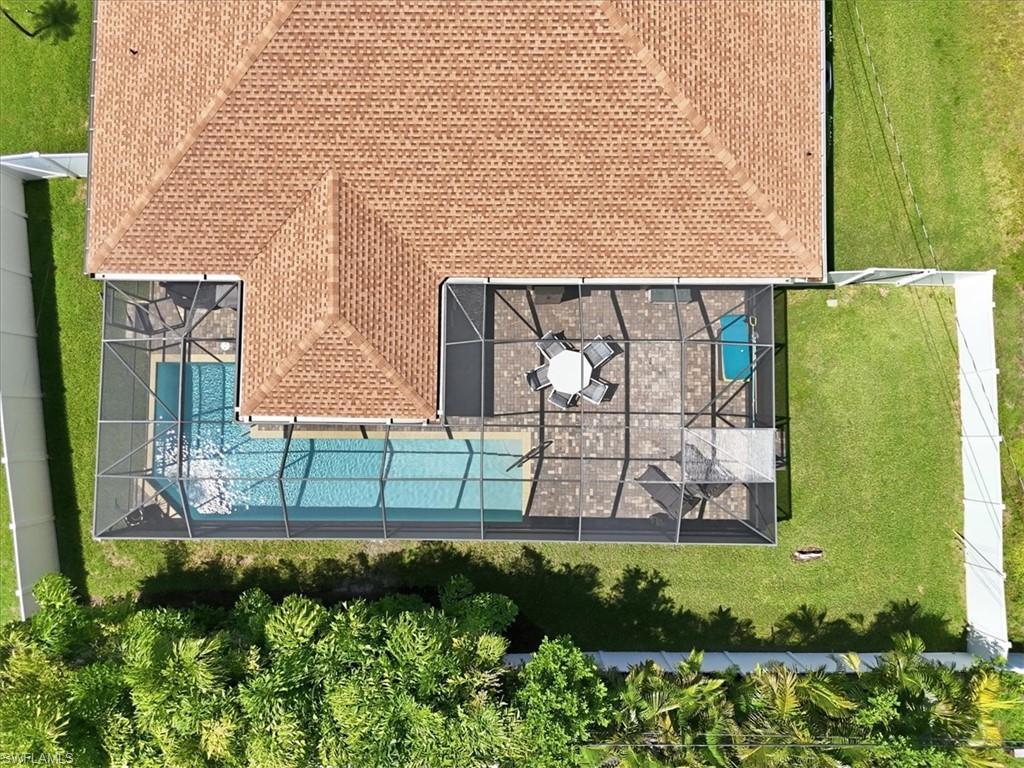 Expansive screened-in pool enclosure featuring a large pool, tiled patio, and a separate spa
