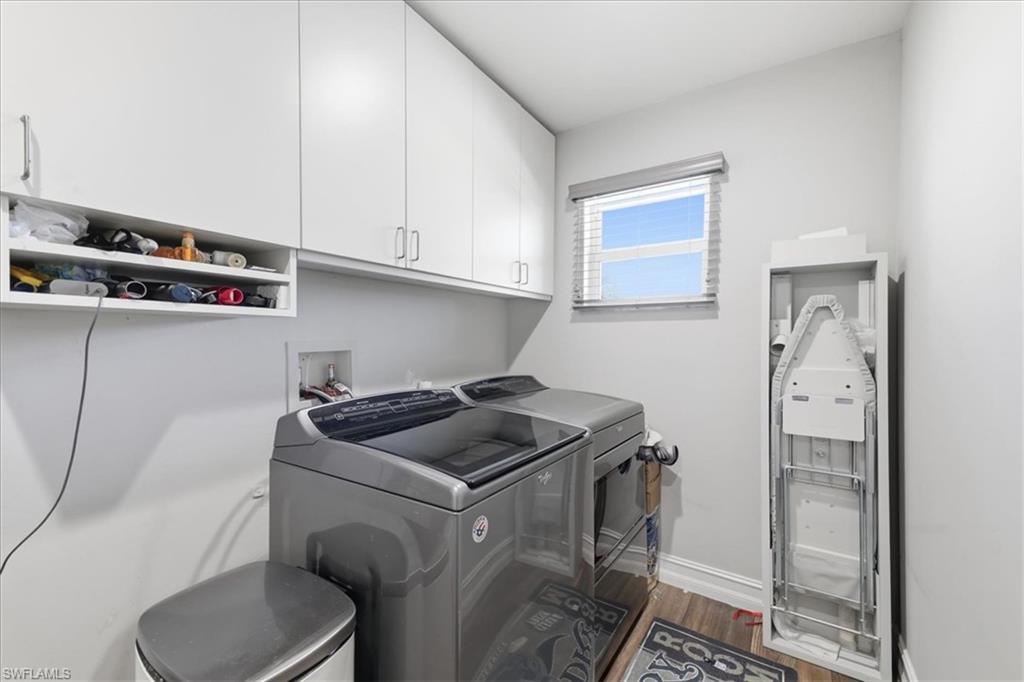 Laundry area featuring upper cabinetry, a window with blinds, wood-finish flooring, and light-toned walls