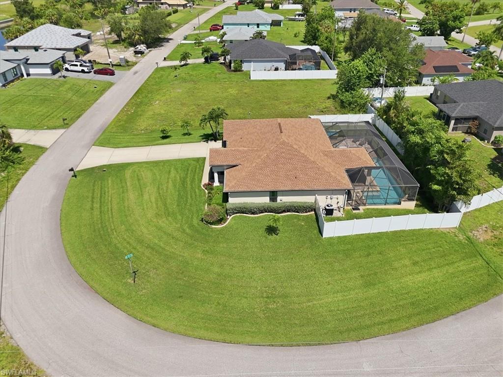 Corner lot residence featuring a screen-enclosed pool, vinyl privacy fencing, and a manicured lawn