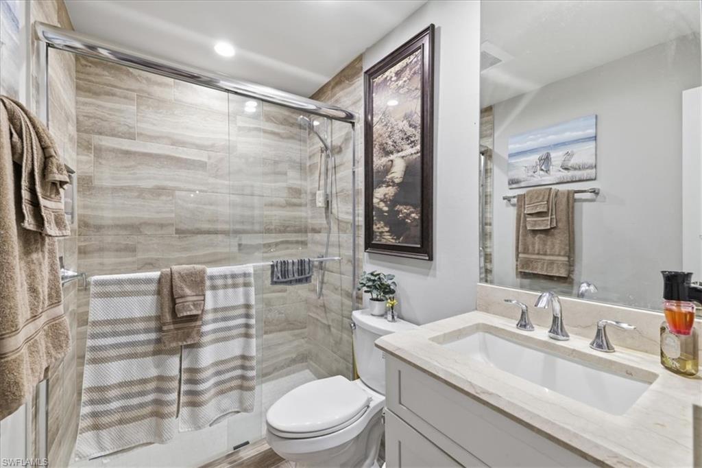 Bathroom featuring a glass-enclosed shower with full-height tile surround, a built-in vanity with an integrated sink, polished chrome fixtures, and overhead recessed lighting