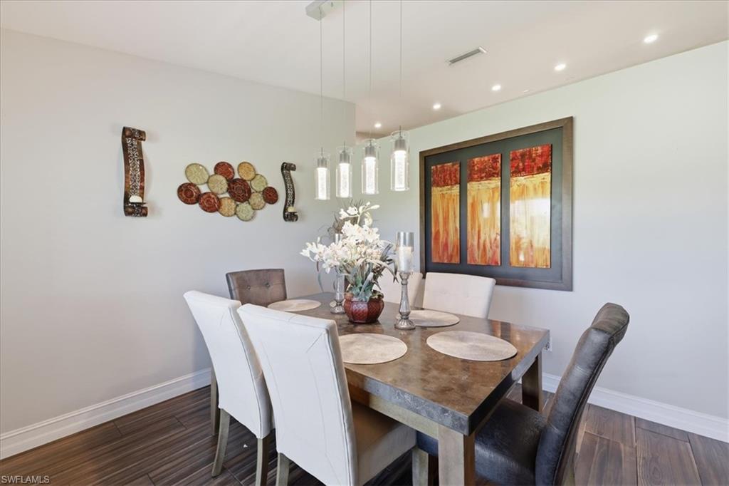 Dining area featuring wood-finish flooring, recessed lighting, and a modern linear pendant light fixture