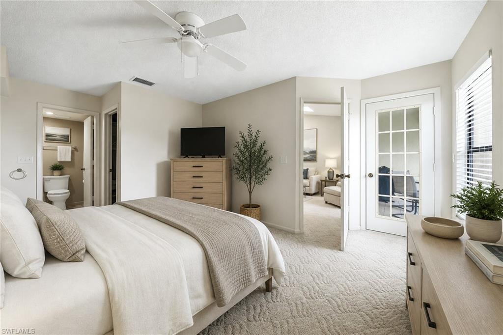 Carpeted bedroom with a ceiling fan, a private bathroom, and a glass-paned door