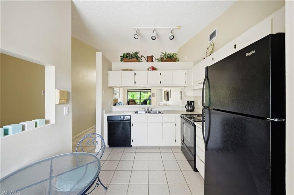Kitchen featuring white cabinetry, light countertops, and black appliances