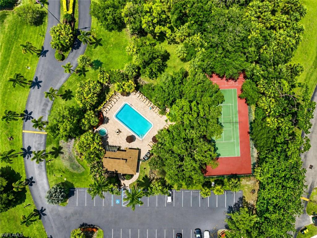 Community amenities featuring a swimming pool, spa, tennis court, and covered pavilion, surrounded by mature landscaping and a parking area