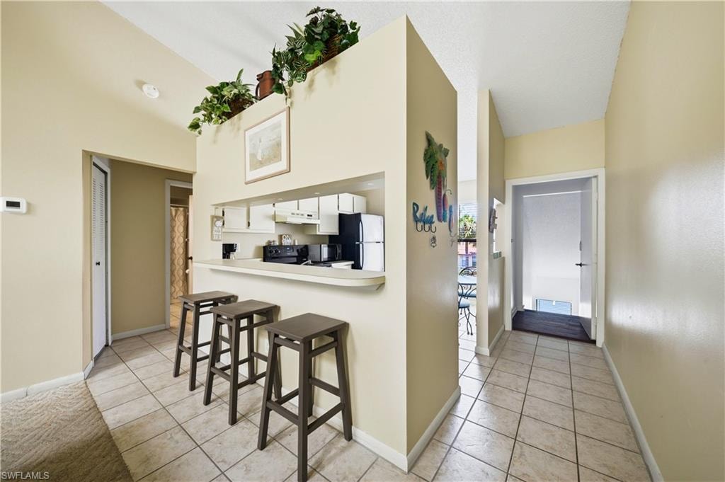 Kitchen pass-through with breakfast bar, featuring white cabinetry, a black range, and built-in shelving
