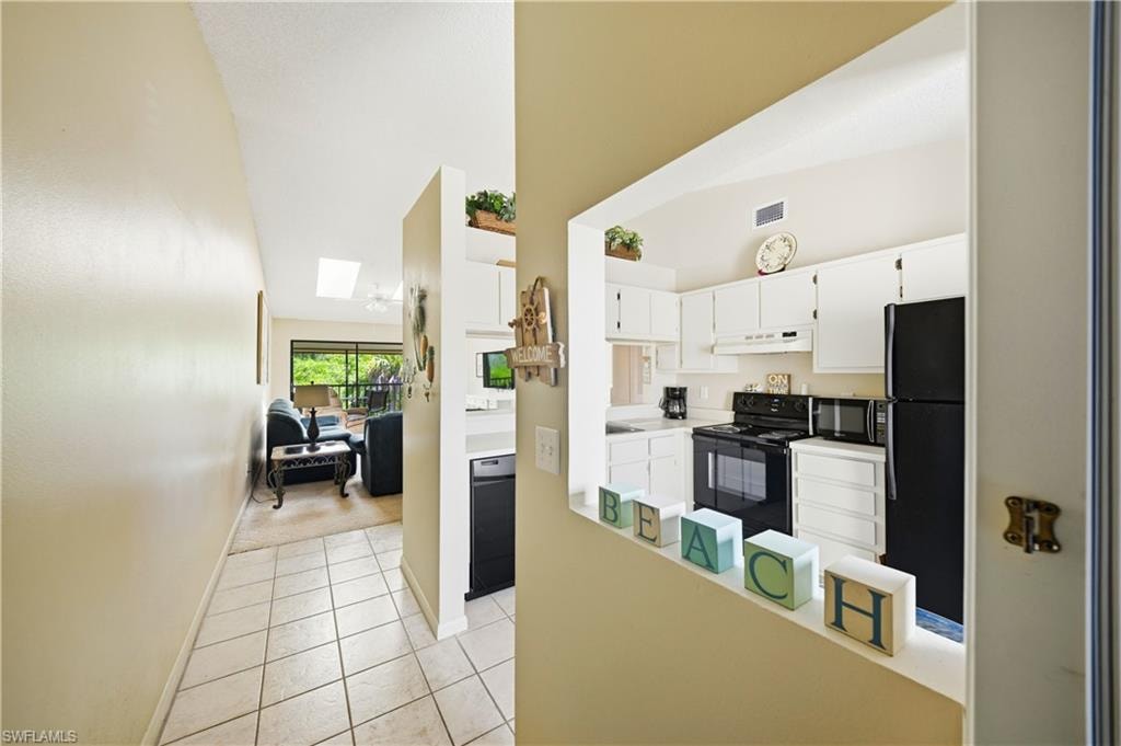 Kitchen featuring white cabinetry, black appliances, and a pass-through window