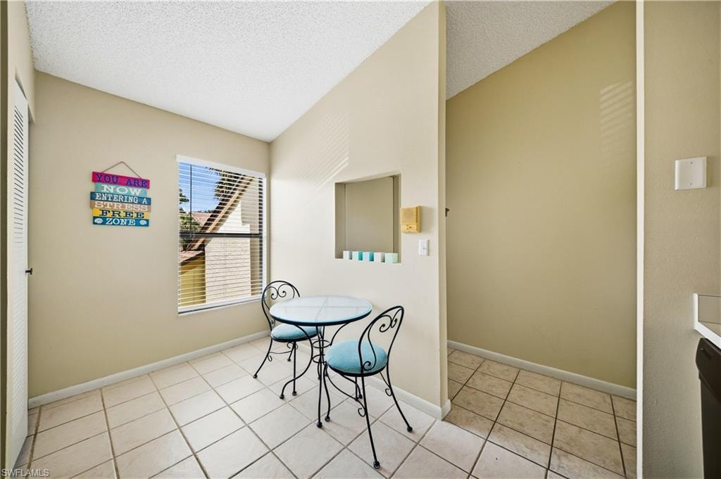 Kitchen dining area featuring a window with blinds, tile flooring, and a recessed wall niche