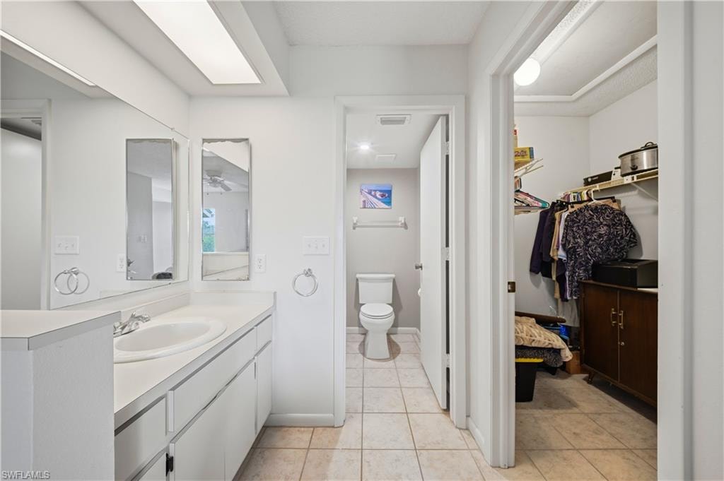 Bathroom featuring a vanity with an integrated sink, two wall-mounted mirrors, and an adjacent water closet