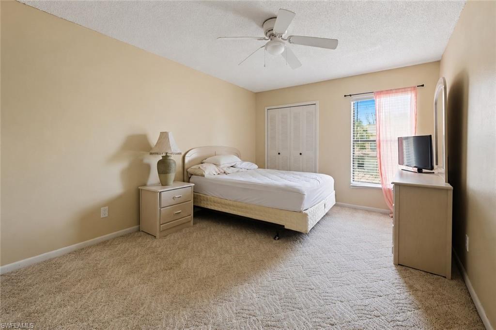 Bedroom featuring wall-to-wall carpeting, neutral wall tones, a ceiling fan, a window with blinds and sheer curtains, and bi-fold closet doors