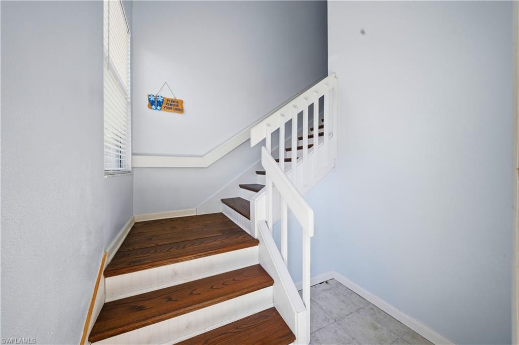 Staircase featuring wood-finish treads, white risers, and a white balustrade