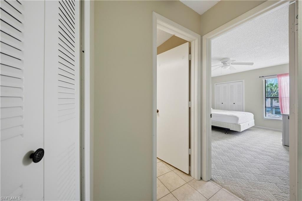 Carpeted bedroom featuring a ceiling fan, a white paneled door with glass inserts, a window with blinds, and a private attached bathroom with a toilet