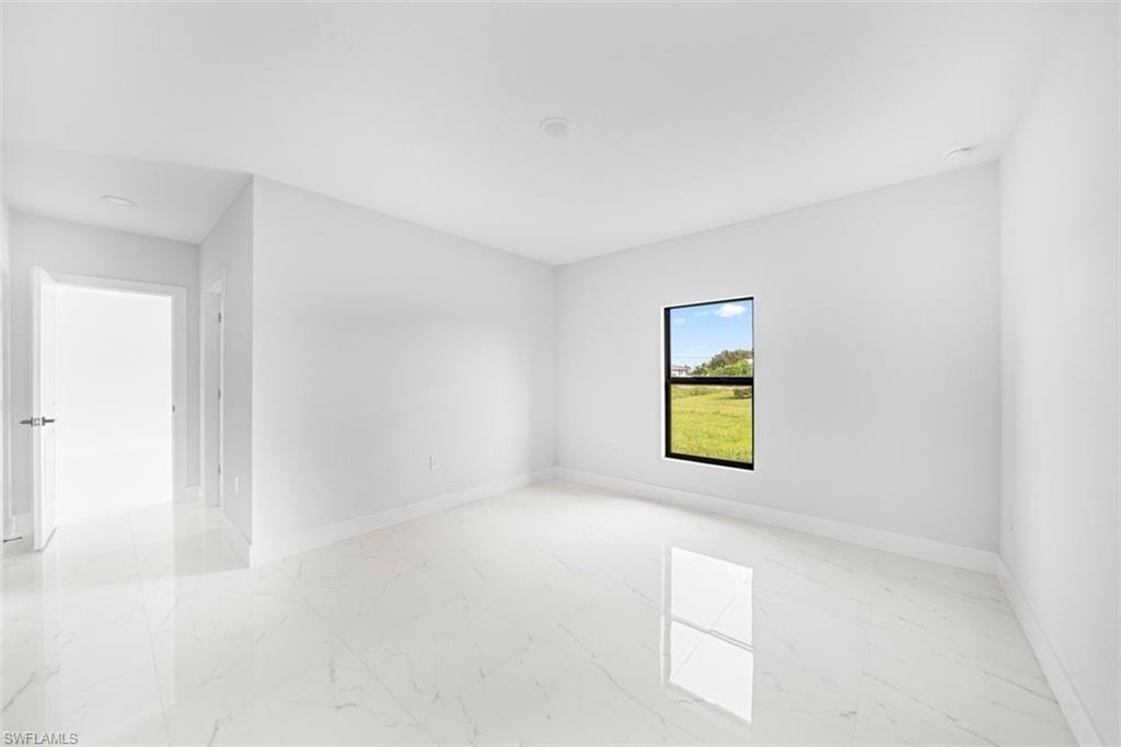 Spacious room featuring large format tile flooring, a single window with black trim, and recessed ceiling lighting