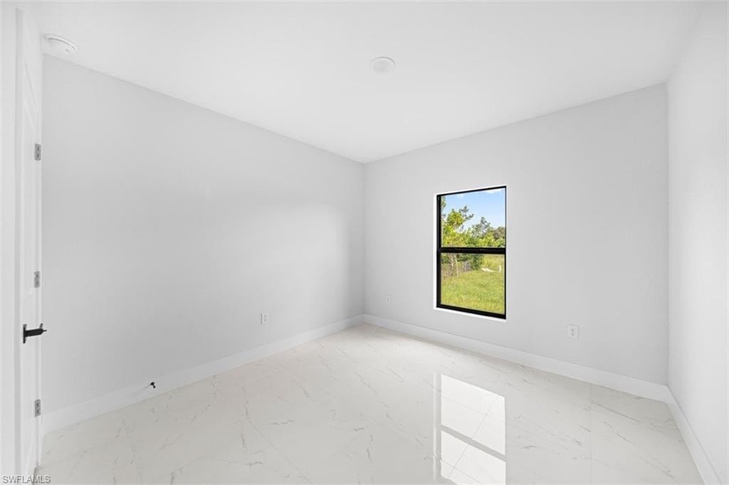Bright room featuring a single-pane window with black trim, white walls, and white baseboards
