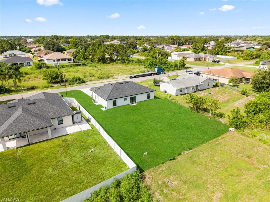Newly constructed residence featuring a white exterior, dark shingle roof, and an expansive manicured lawn