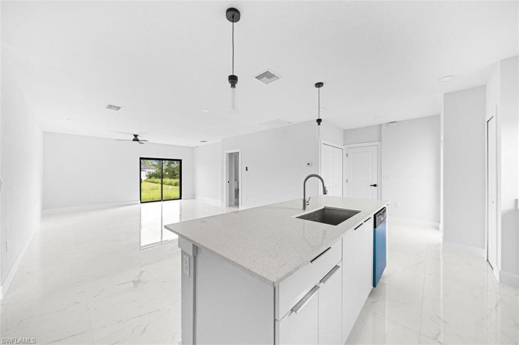 Open-concept living space featuring a central island with an undermount sink and a dark-finish faucet