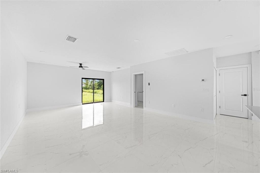 Spacious interior featuring large format tile flooring, a contemporary ceiling fan, and sliding glass doors