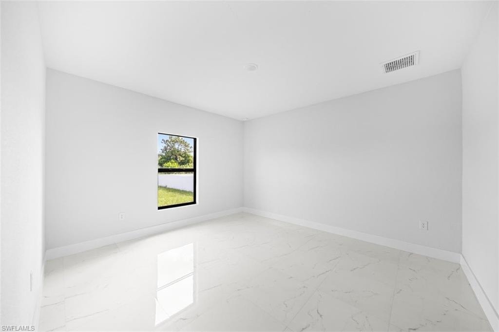 Bright interior space featuring large format tile flooring, a single window with black trim, white painted walls, and a ceiling-mounted ventilation register