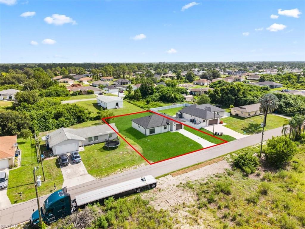 Aerial perspective showcasing a contemporary residence with a dark shingle roof and a vibrant green lawn