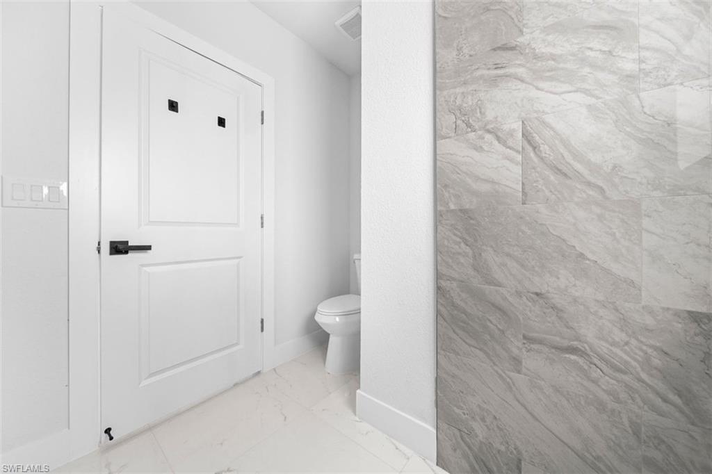 White paneled door with black hardware, complemented by a light-toned tile floor