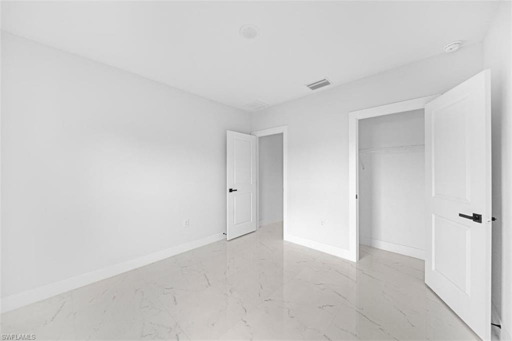 Spacious room featuring white walls, white trim, and white doors with matte black hardware