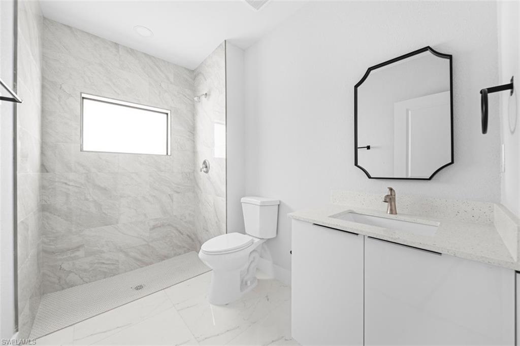 Modern bathroom featuring a walk-in shower with large format tile surround and a rectangular window