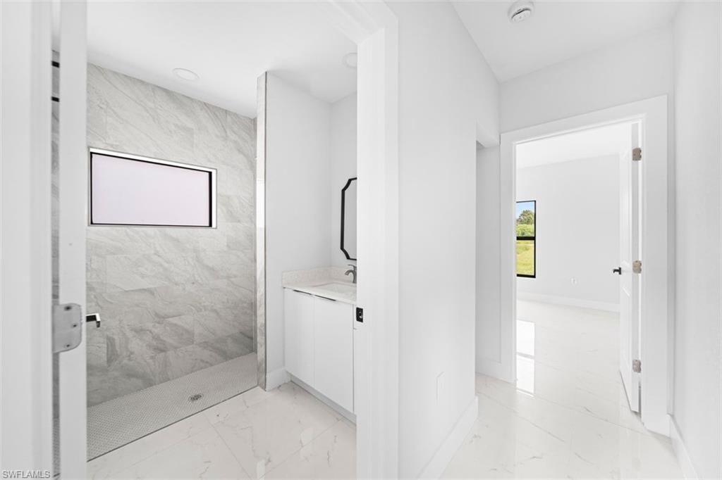 Contemporary bathroom with a walk-in shower featuring gray stone-look tile, a rectangular window, and a glass enclosure