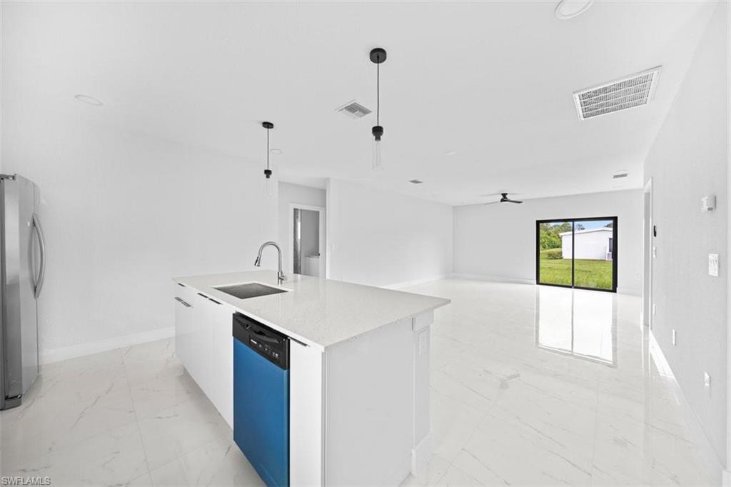 Kitchen island with a white countertop and integrated sink, featuring a stainless steel faucet and blue-paneled dishwasher