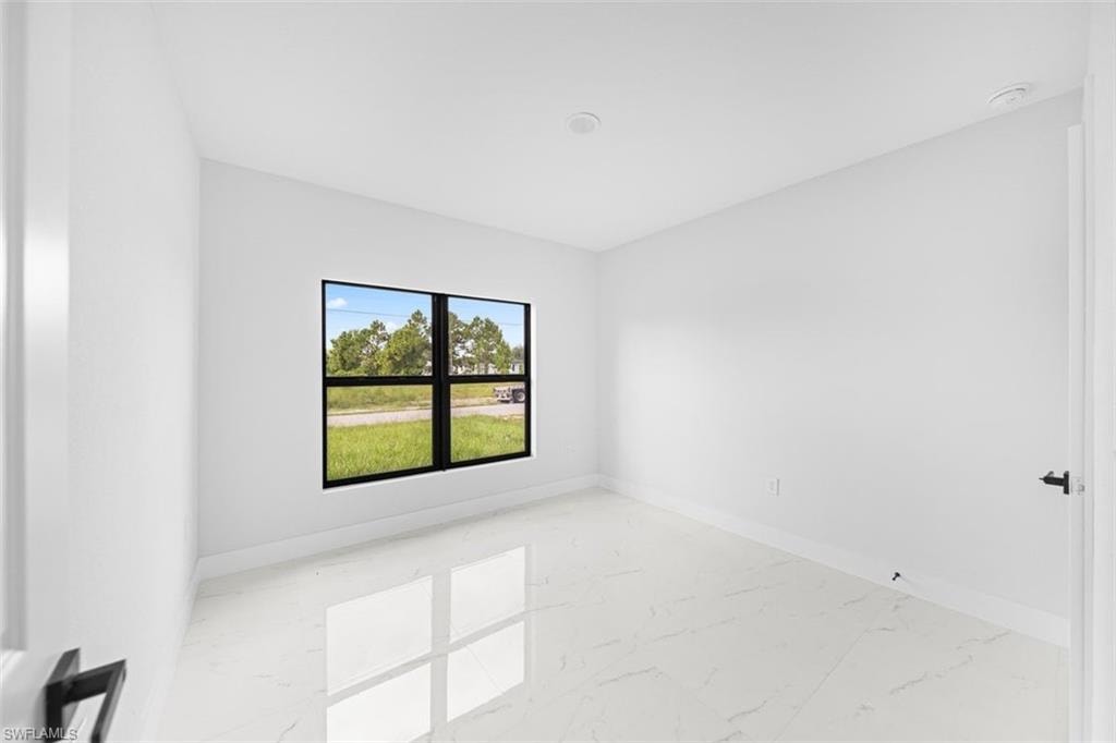 Bright room featuring a large black-framed window, white walls, and white tile flooring