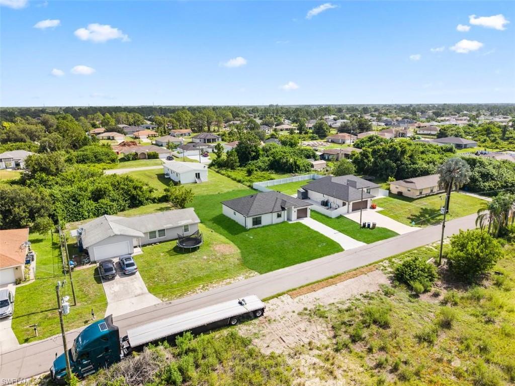Aerial perspective showcasing multiple properties with paved roads and a mix of manicured lawns and undeveloped land