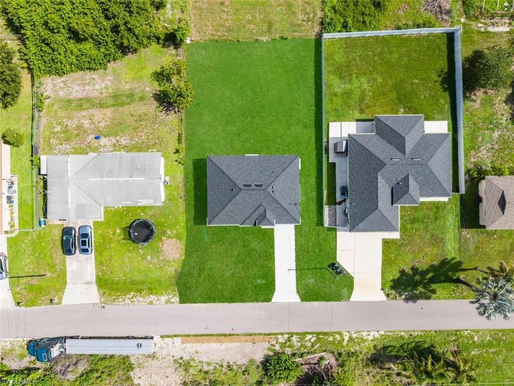 Aerial overview featuring a residential property with a dark shingle roof and a light-toned driveway