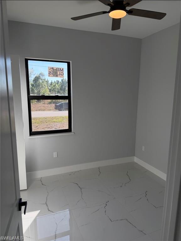 Interior room featuring light gray walls, white baseboards, and large format tile flooring with a white and gray veined pattern