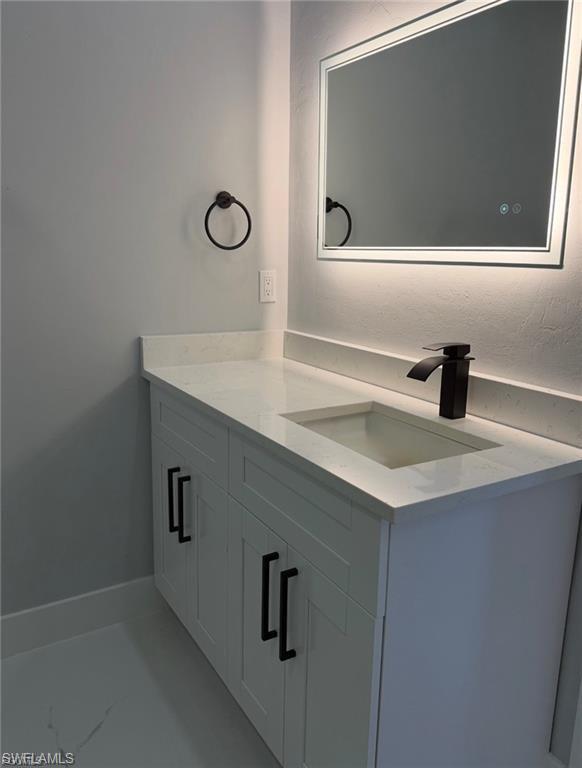Modern vanity featuring a white countertop with integrated sink, matte black faucet, and contemporary lighting