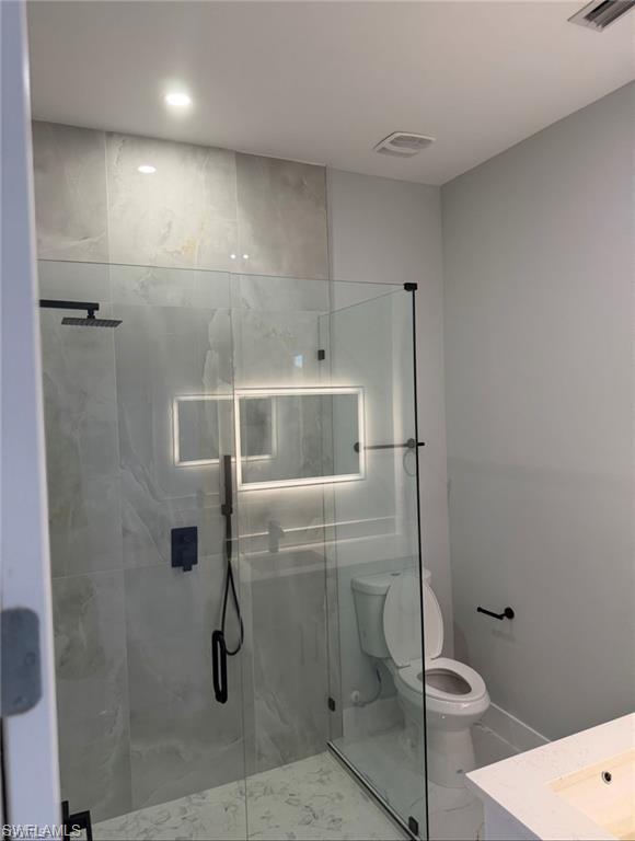 Modern bathroom featuring a glass-enclosed shower with matte black fixtures, an illuminated mirror, and large format wall tiling