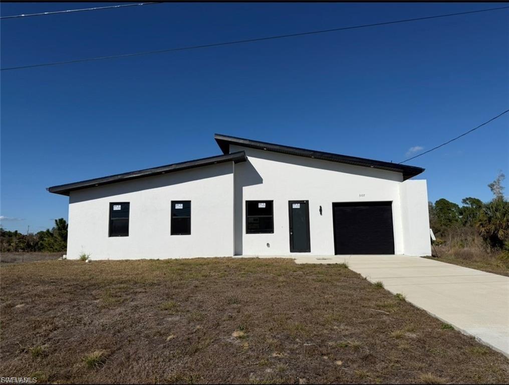 Contemporary single-story exterior featuring a white stucco finish and a black sloped roofline