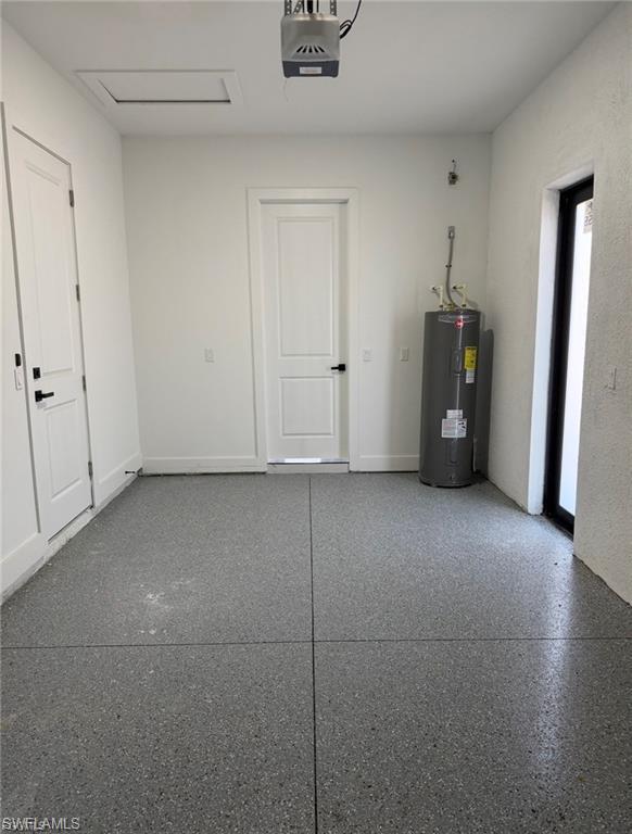 Garage interior featuring a gray speckled epoxy floor, white painted walls, and a visible water heater
