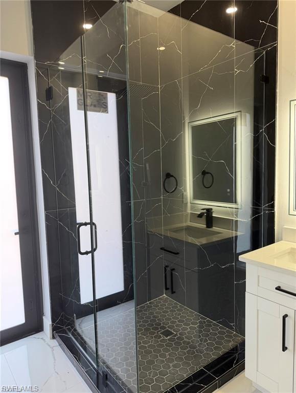 Glass-enclosed shower featuring black marble-style tile walls, a hexagonal mosaic tile floor, and a matte black shower head