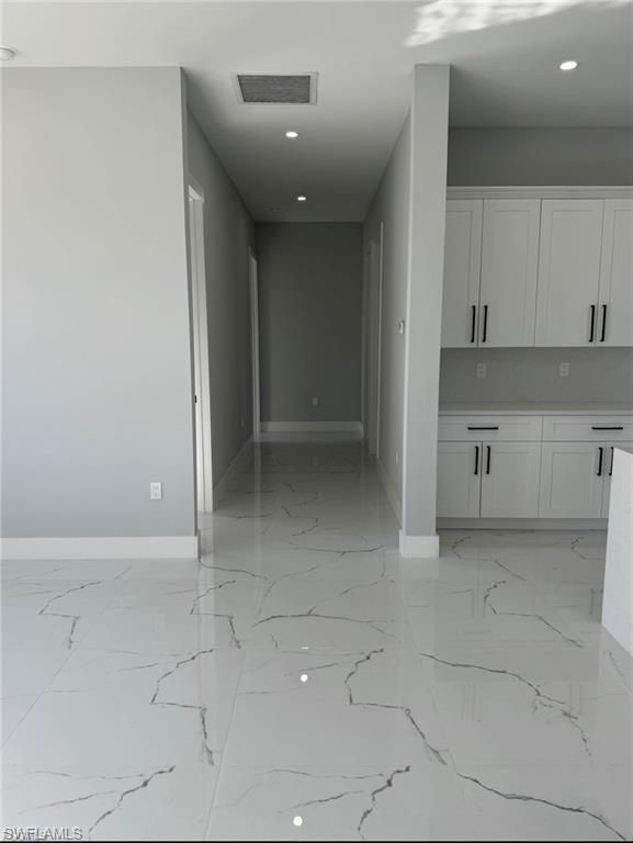 Interior hallway featuring white tile flooring with gray veining and recessed lighting