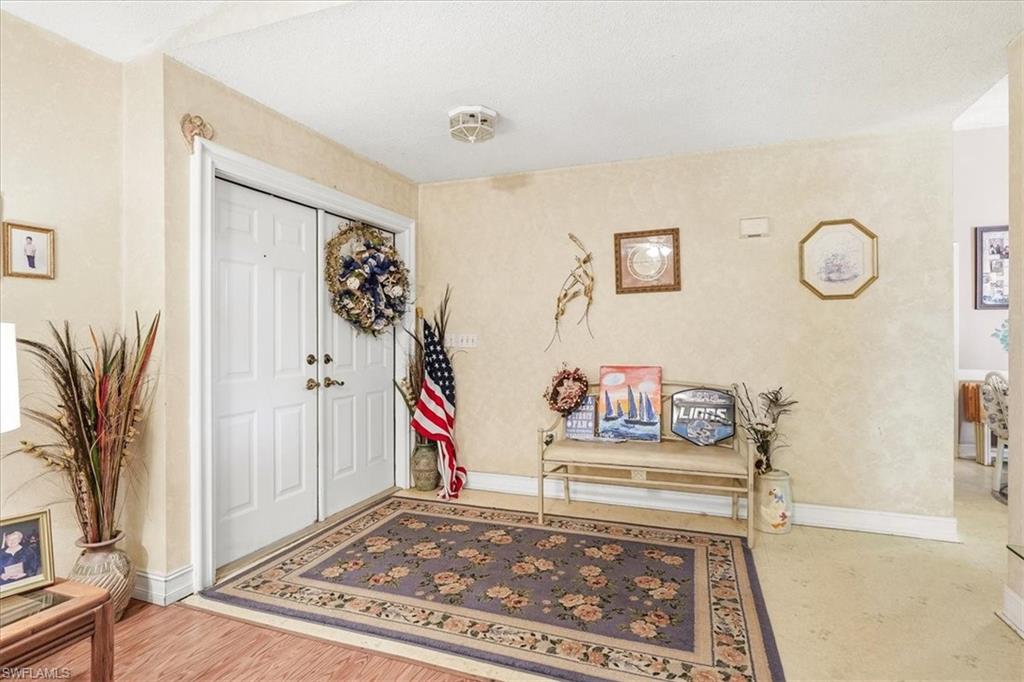 Entryway featuring double white doors, wood-finish flooring, and light-toned walls