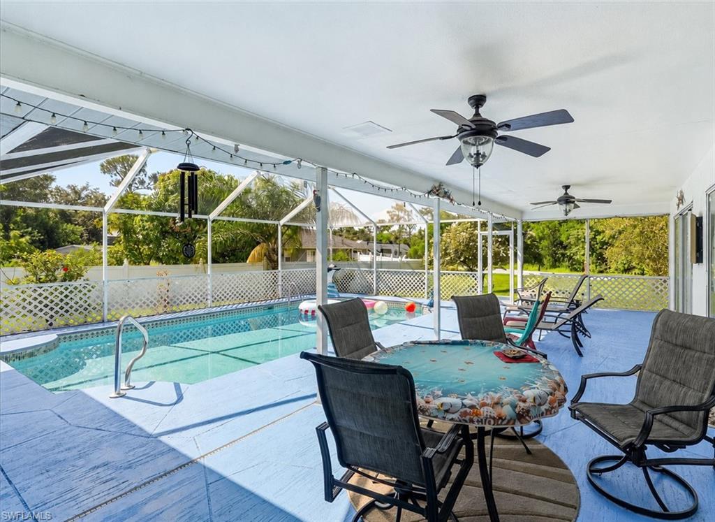 VIRTUALLY STAGED Screened-in pool area featuring a rectangular pool, concrete decking with blue finish, and multiple ceiling fans