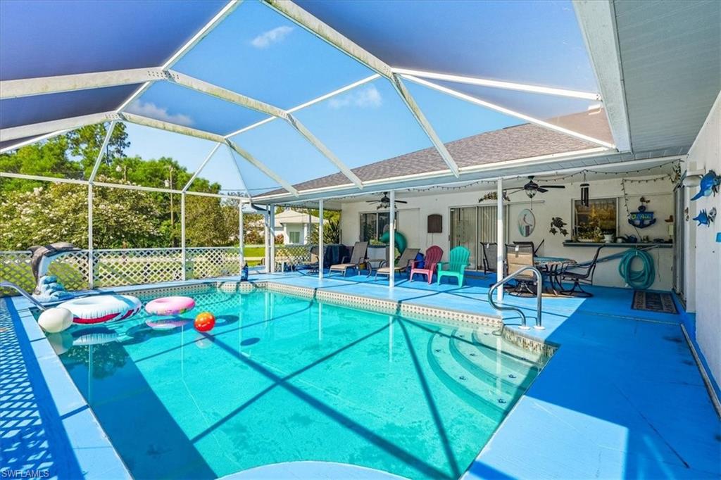 Screened-in swimming pool enclosure featuring an in-ground pool with steps, a paved pool deck, and a covered patio area
