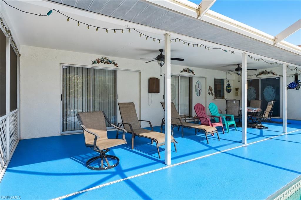 VIRTUALLY STAGED Expansive covered patio featuring a vibrant blue concrete surface, multiple ceiling fans, and direct access to interior spaces through sliding glass doors