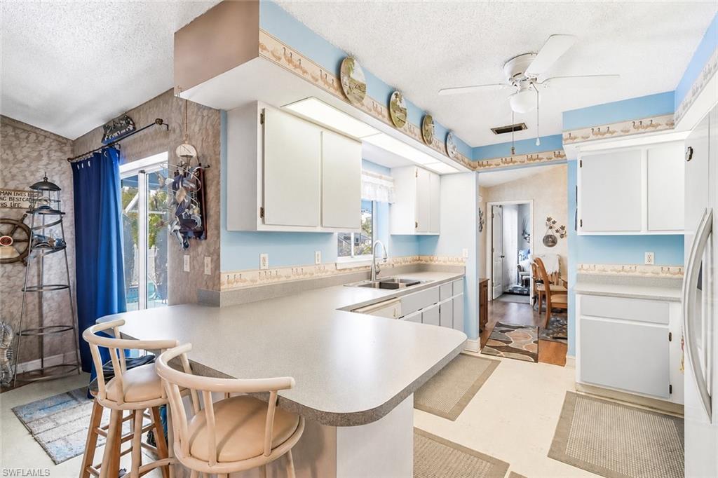 VIRTUALLY STAGED Kitchen featuring white cabinetry, light-toned countertops, an undermount sink, and recessed lighting