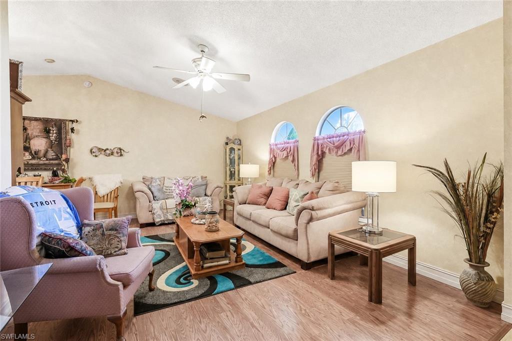 Living area featuring vaulted ceilings, wood-finish flooring, and two arched windows
