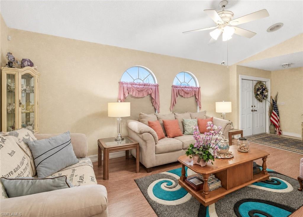 Living area featuring wood-finish flooring, a ceiling fan, and arched windows
